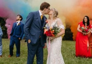 bride and groom kissing with colored smoke in background