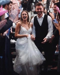 bride and groom smiling and laughing surrounded by guests